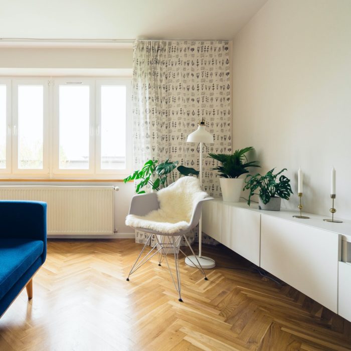 apartment space with blue couch, white chair and tv