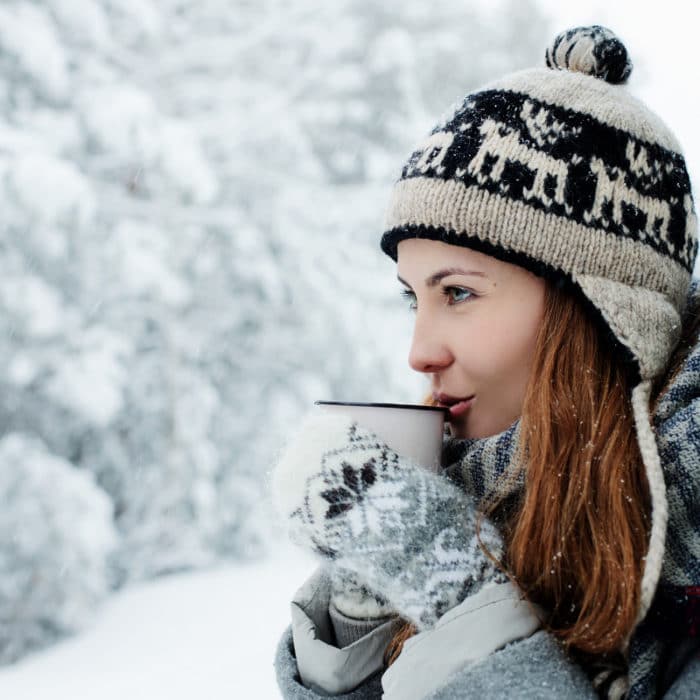 woman sipping coffee in the snow knitted items