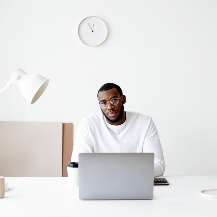 man on laptop with a white desk and flowers