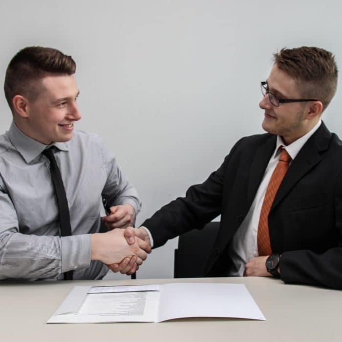 two men at a desk shaking hands