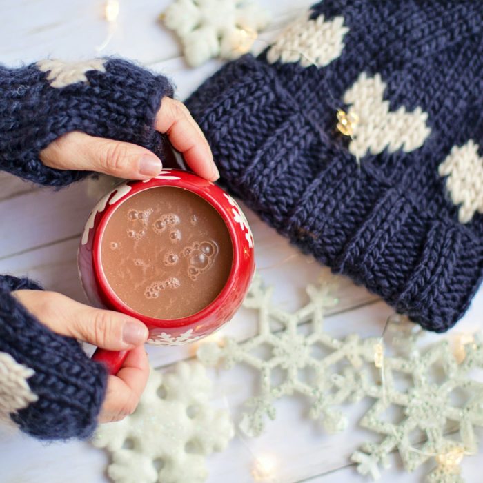 woman holding hot chocolate knitted mittens hat