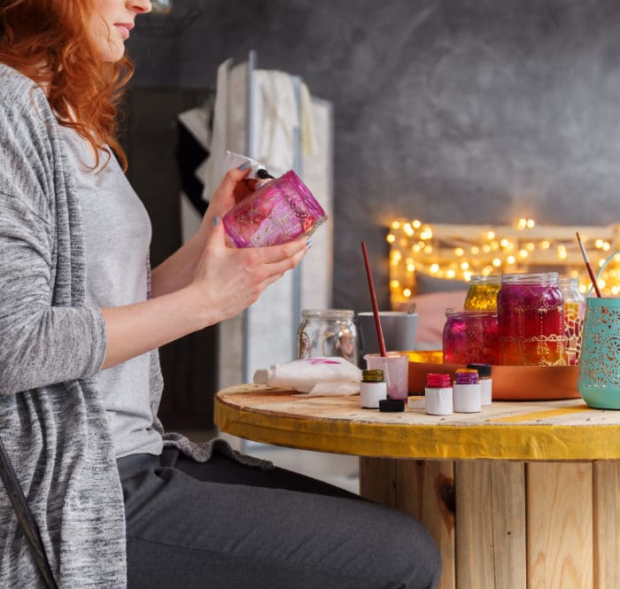 woman painting jars at a table