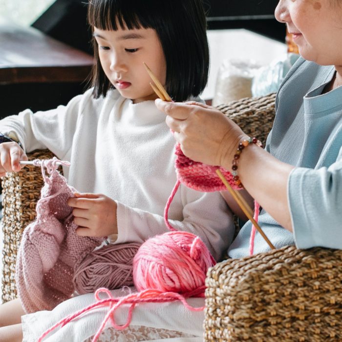 woman teaching child to knit