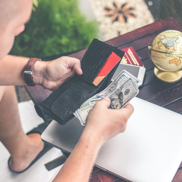 man putting cash in wallet