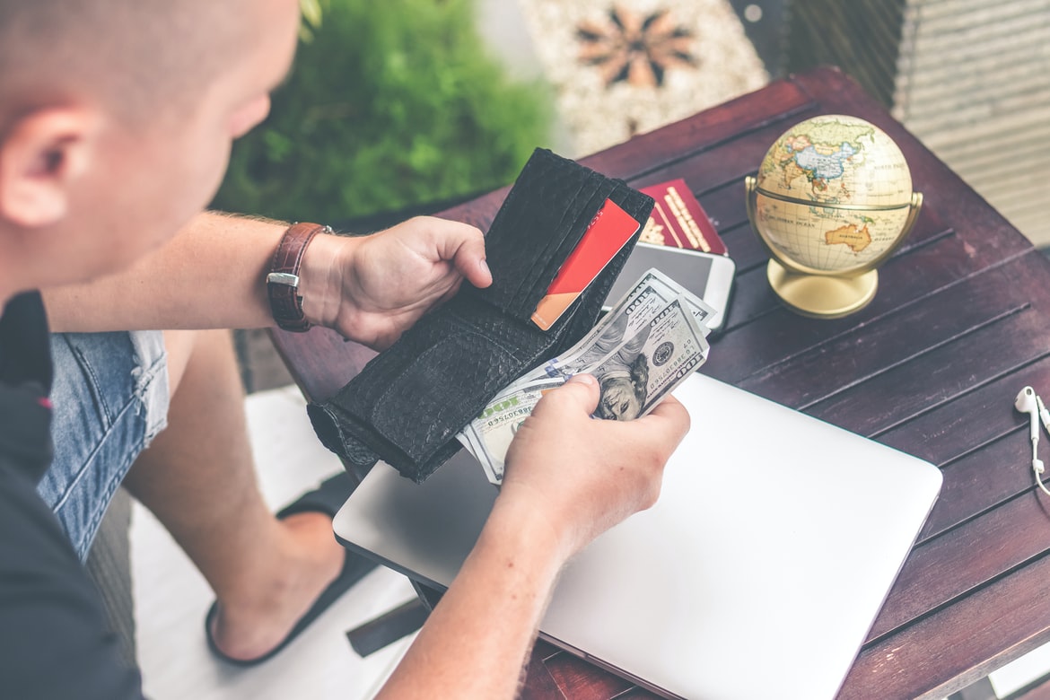 man putting cash in wallet